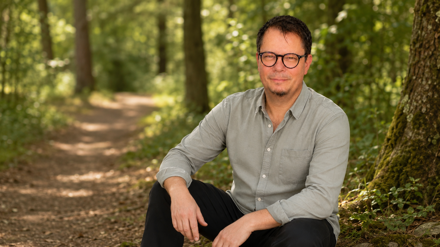 Tom Steiner – Zertifizierter PEMF-Praktiker für Regeneration und Achtsamkeit, entspannt sitzend im Wald als Zeichen für Ruhe und Entschleunigung.